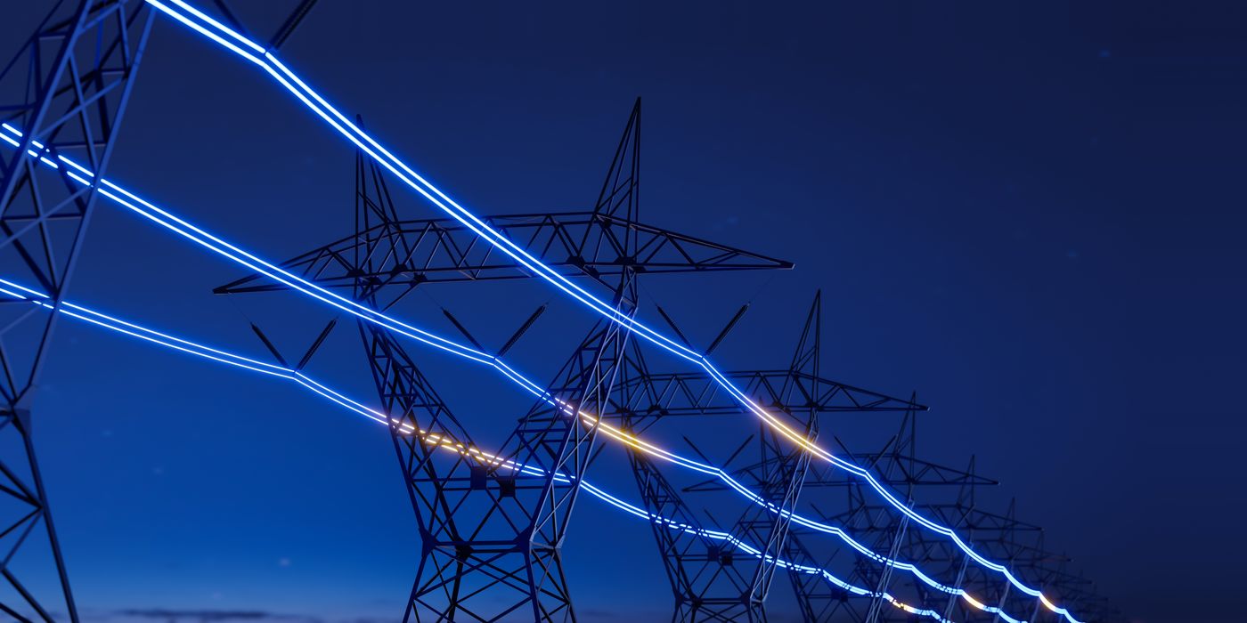 High-voltage transmission towers at dusk with illuminated conductors